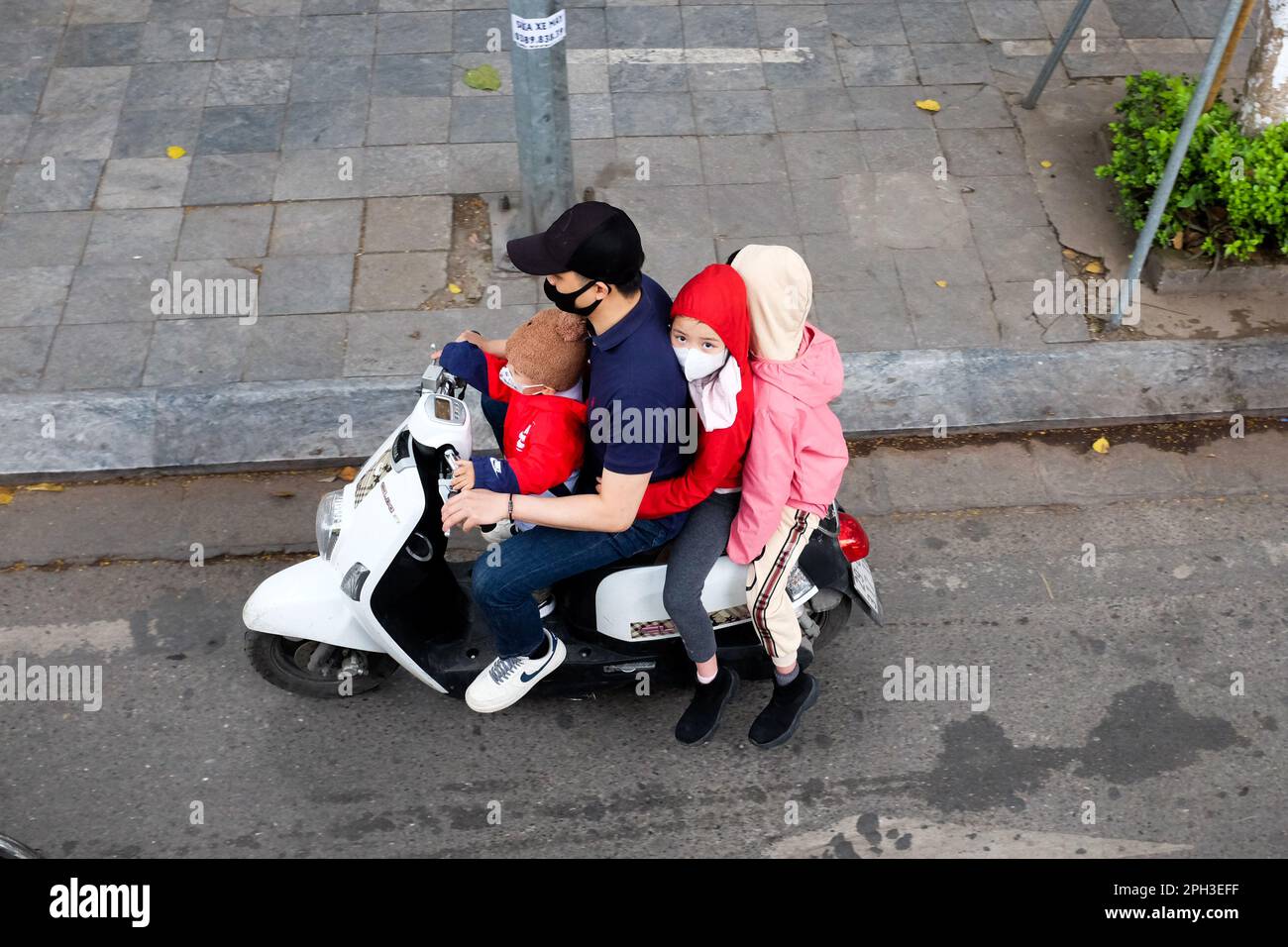 A child and two adults riding on a moped in Hanoi, Vietnam, in 2023