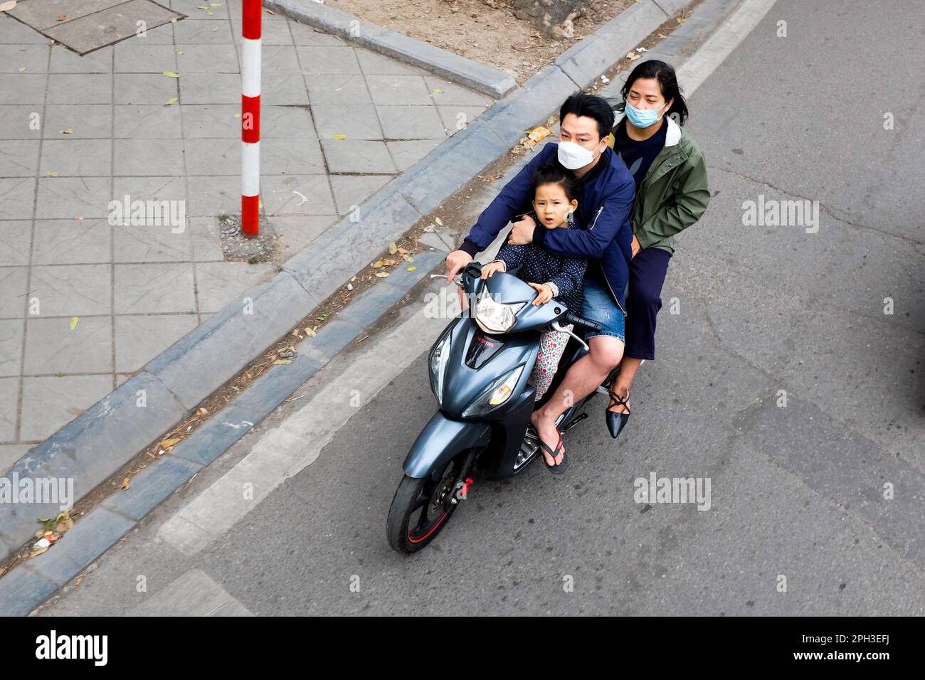 A child and two adults riding on a moped in Hanoi, Vietnam, in 2023