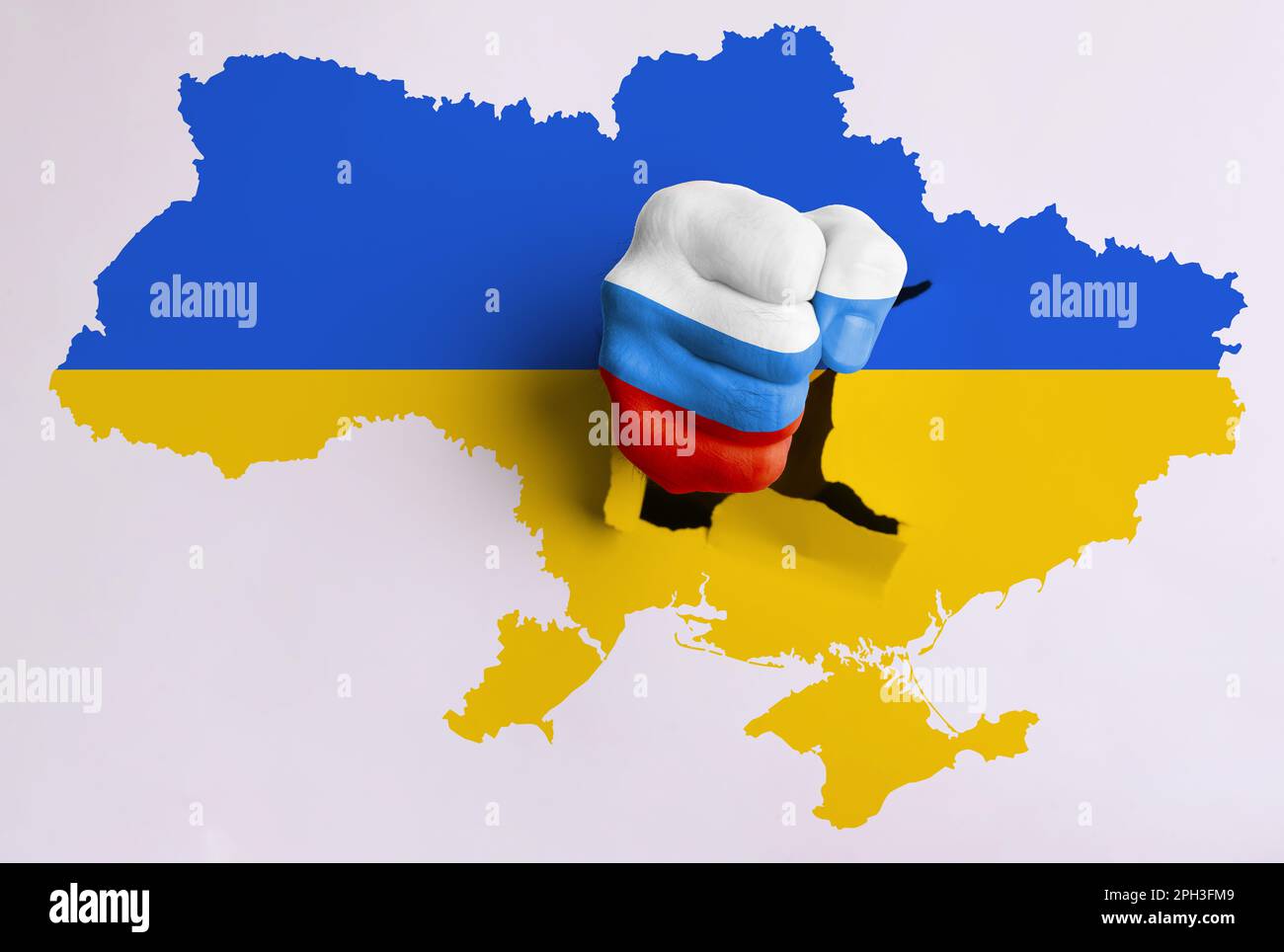 Russian aggression against Ukraine. Man breaking through map of Ukraine with fist painted in colors of Russian flag Stock Photo