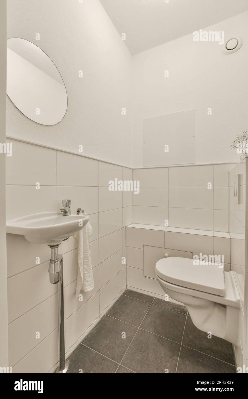 a bathroom with white tiles and gray flooring on the walls, there is a
