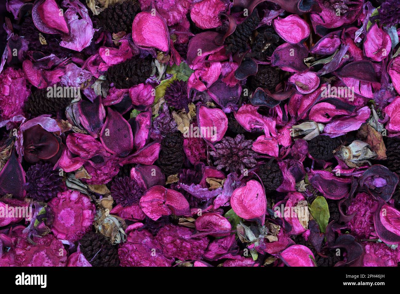 A flat, top view of mostly pink coloured potpourri with dark coloured pine cones and flower buds, filling the frame in soft lighting Stock Photo
