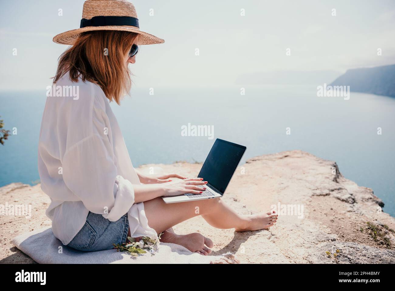 Woman sea laptop. Successful business woman working on laptop by the sea. Pretty lady typing on computer at summer day outdoors. Freelance, digital Stock Photo