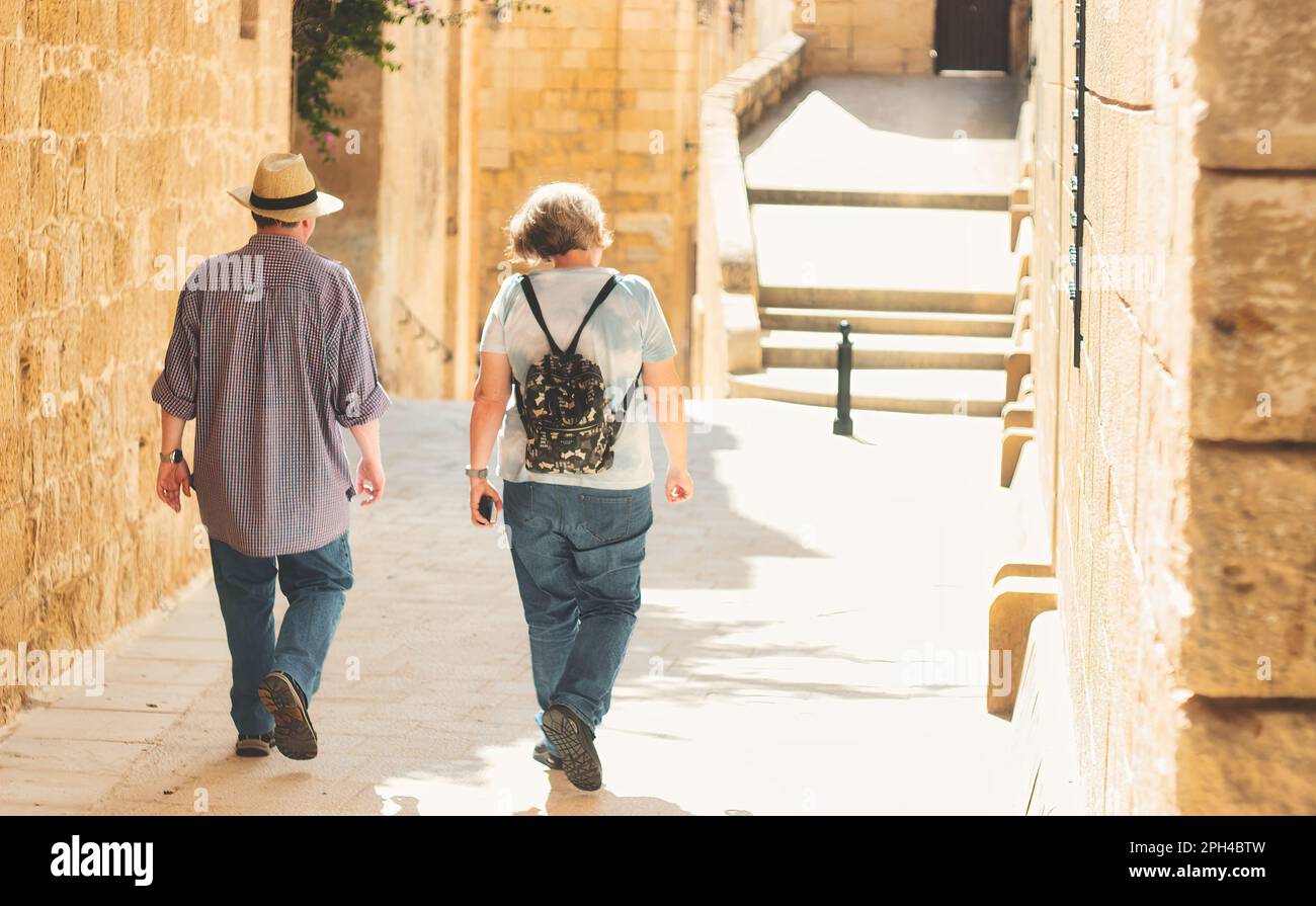 An unrecognizable mature white Caucasian couple of tourists walking ...
