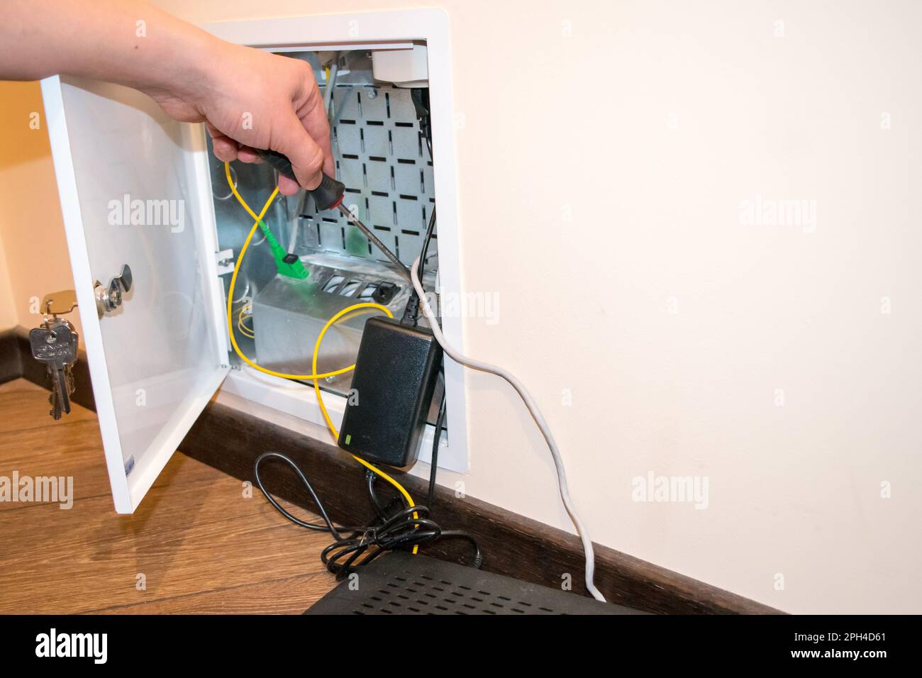 The router box is open, the human hand holds a screwdriver, there is a