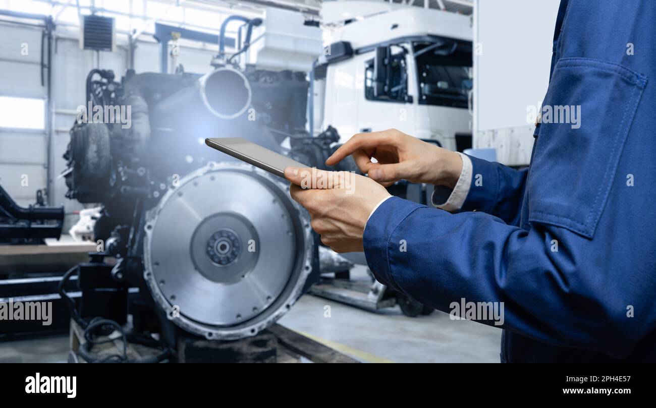 Serviceman with digital tablet on the background of the truck in the garage. High quality photo Stock Photo