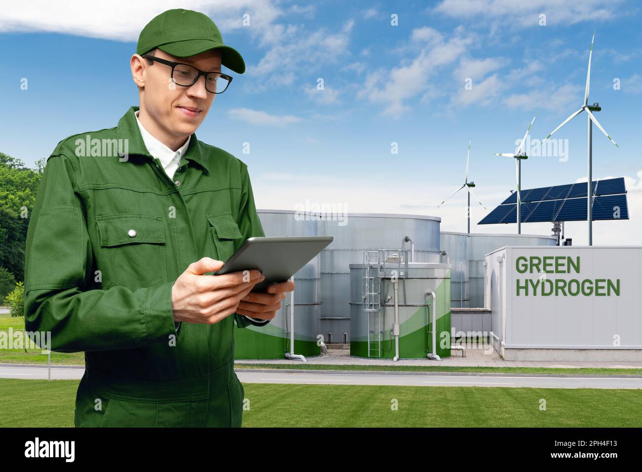 Engineer with tablet computer on a background of green Hydrogen factory. High quality photo Stock Photo