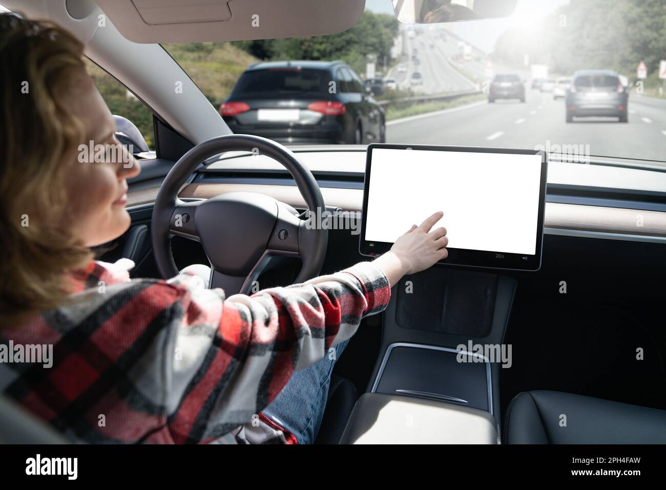 Woman touching car display while her car is driven by an autopilot