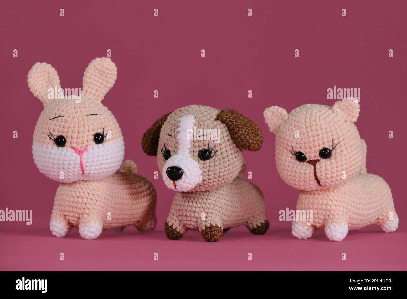 Amigurumi three pets dolls on pink background. DIY soft toys made of