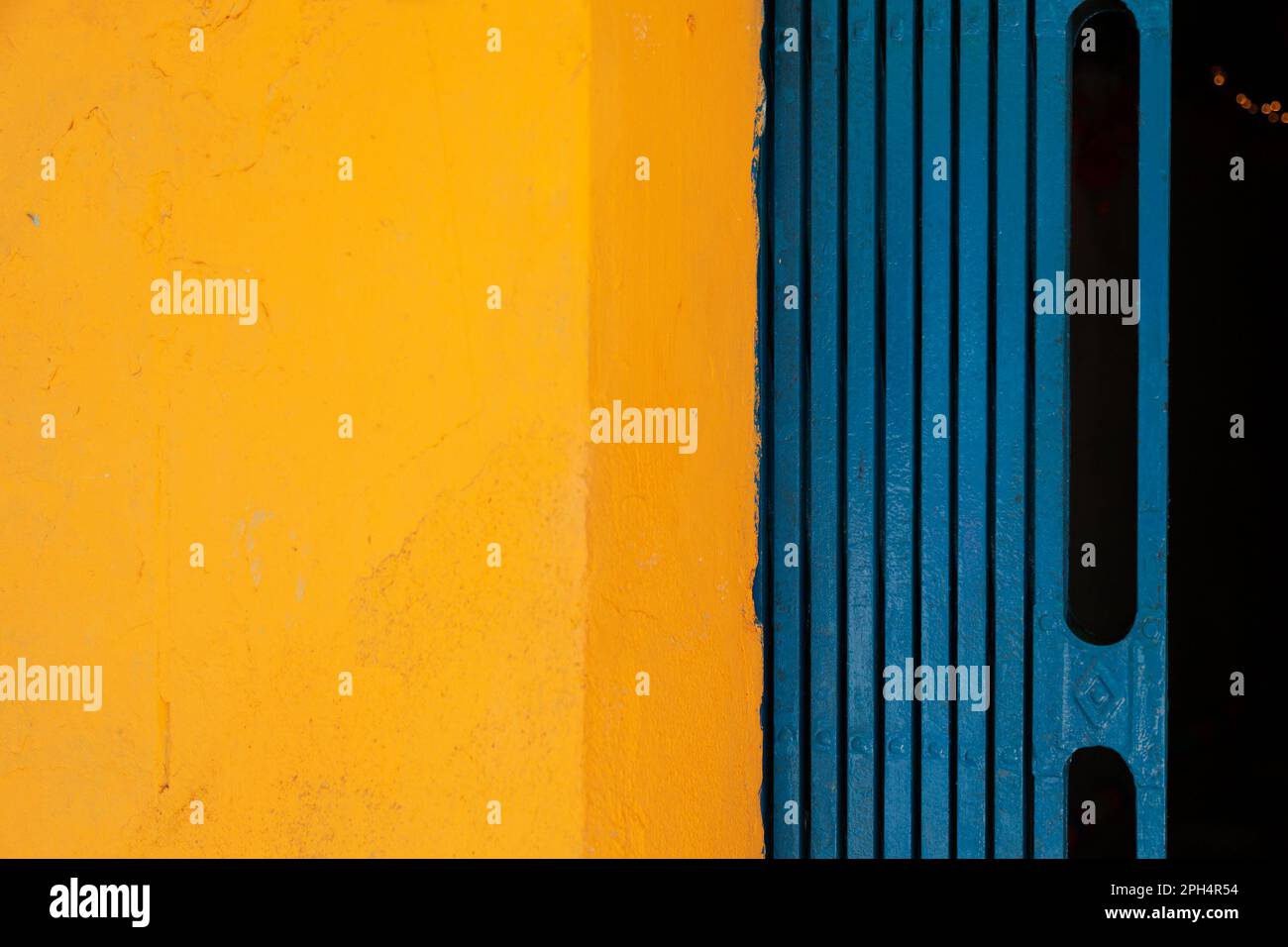 Yellow and blue abstract background divided in two halves vertically. Brightly colored wall and folding gate of a Vietnamese house Stock Photo