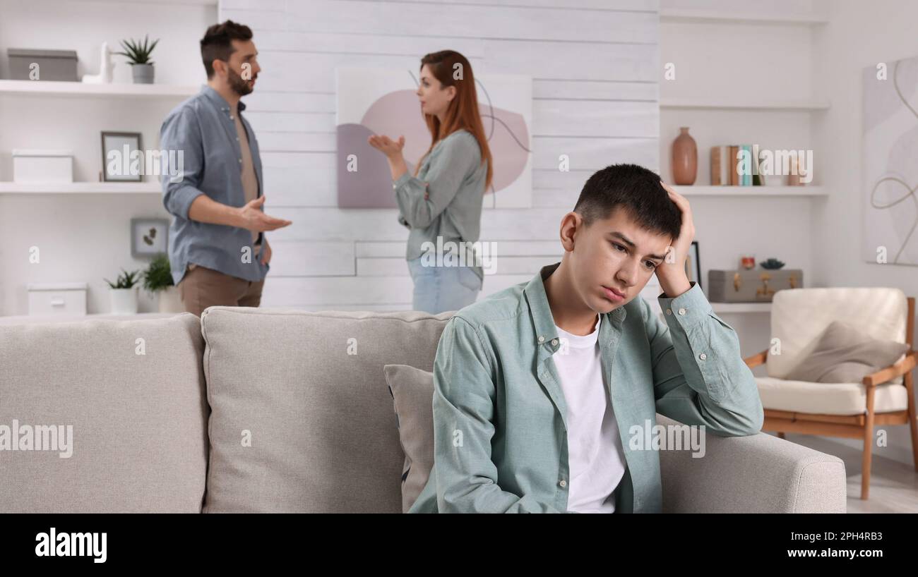 Couple arguing at home, focus on their unhappy teenage boy. Problems in family Stock Photo