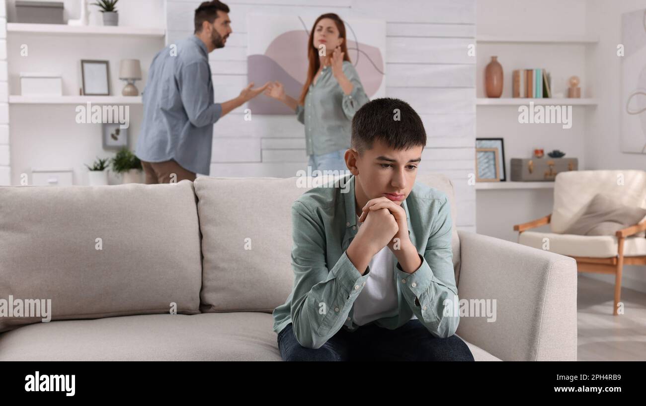 Couple arguing at home, focus on their unhappy teenage boy. Problems in