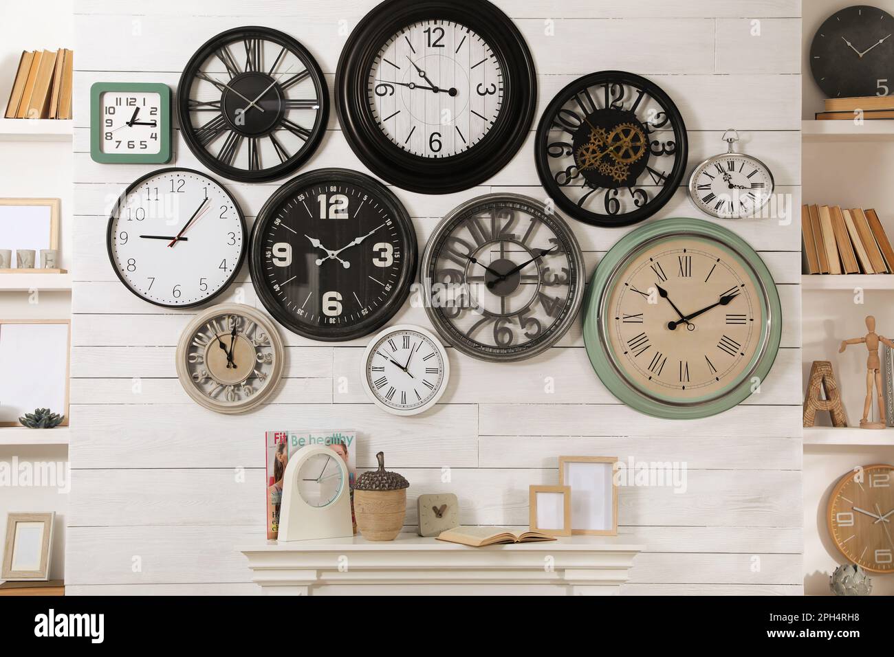 Collection of clocks hanging on white wall above mantel indoors Stock Photo Alamy