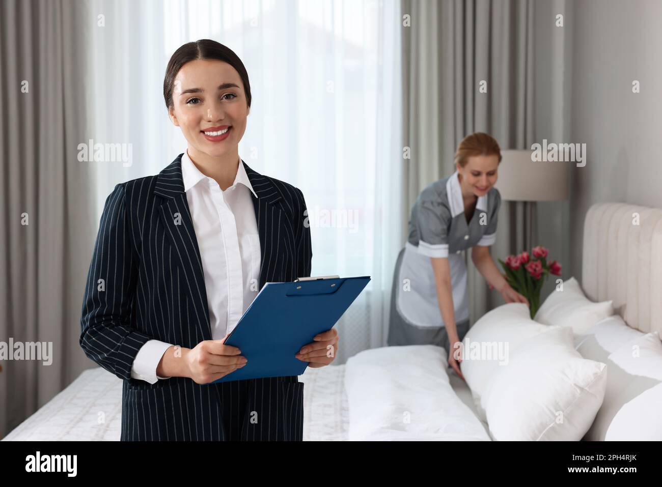 Housekeeping manager with clipboard checking maid's work in hotel
