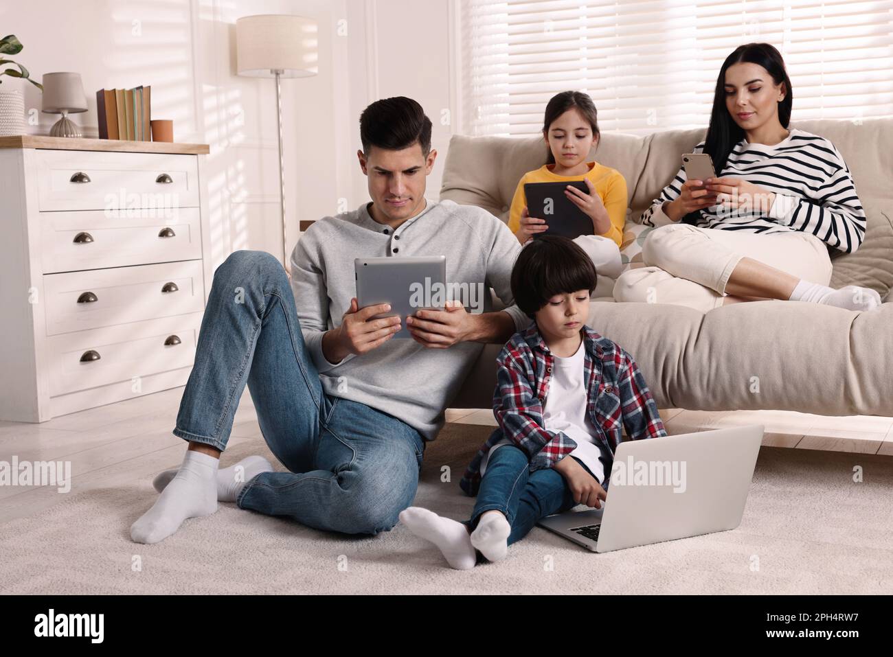 Internet addiction. Family with different gadgets in living room Stock ...