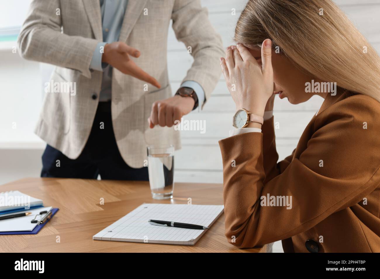 Businessman pointing on wrist watch while scolding employee for being late in office Stock Photo