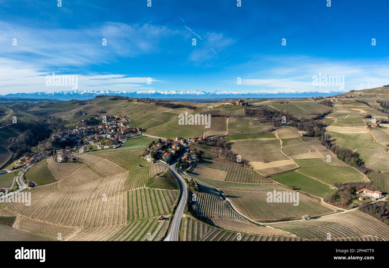 the hilly countryside in the Italian Piedmont with the village of Barolo and snow-covered mountains behind Stock Photo
