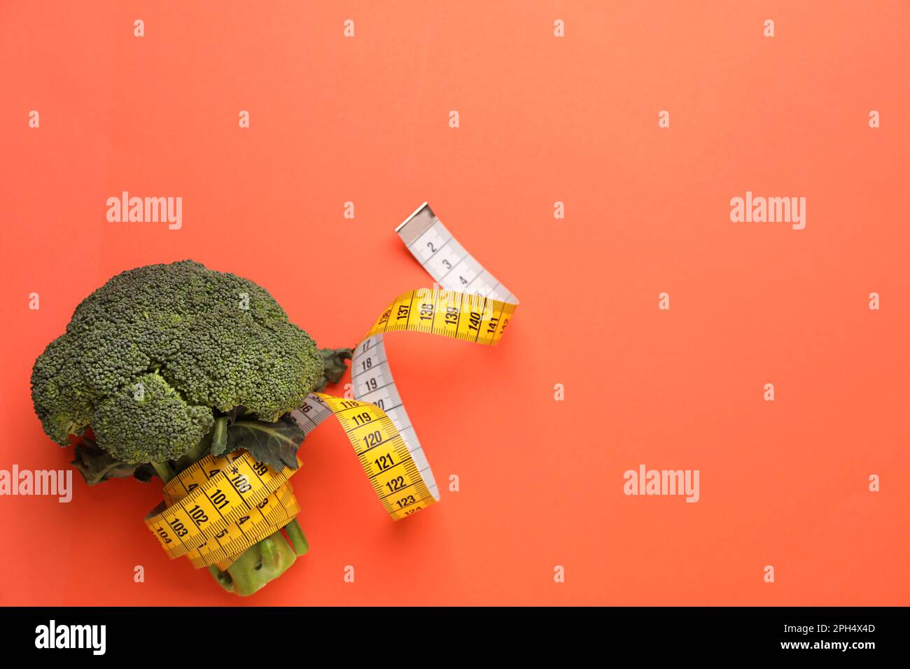 Broccoli and measuring tape on coral background, top view with space for text. Weight loss Stock Photo