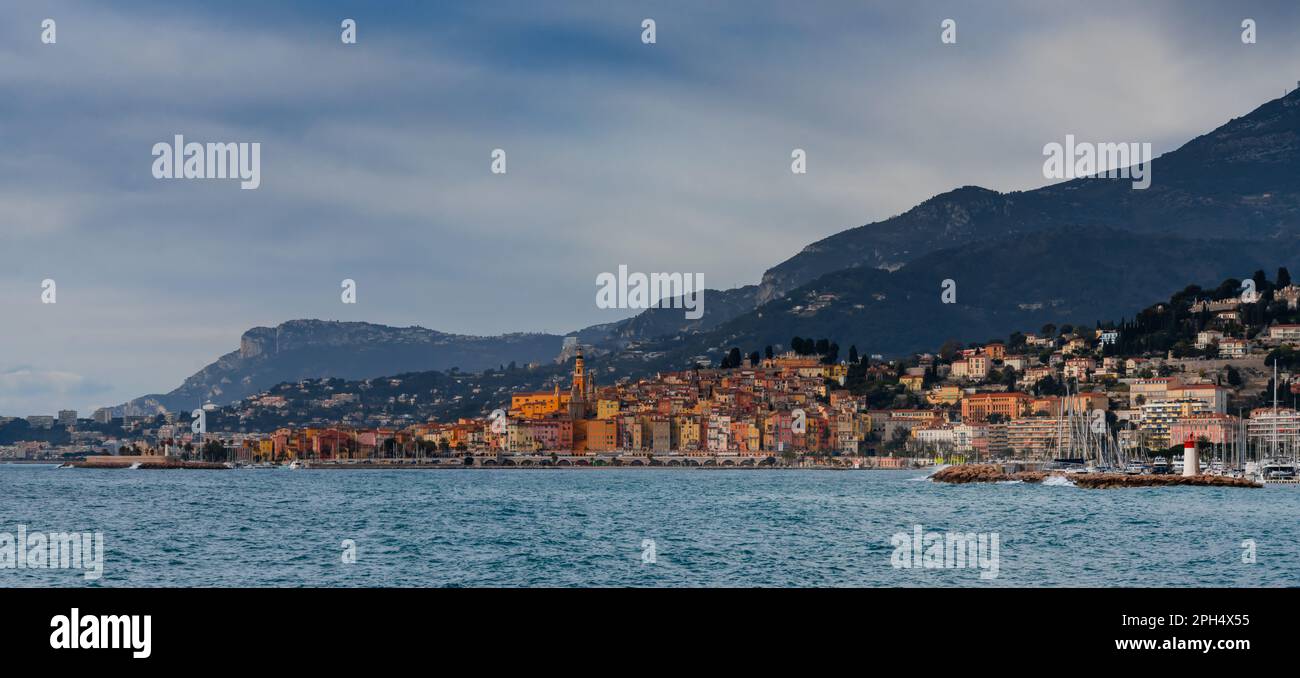 panorama landscape view of the colorful old city center of Menton with the blue Mediterranenan Sea in the foreground Stock Photo