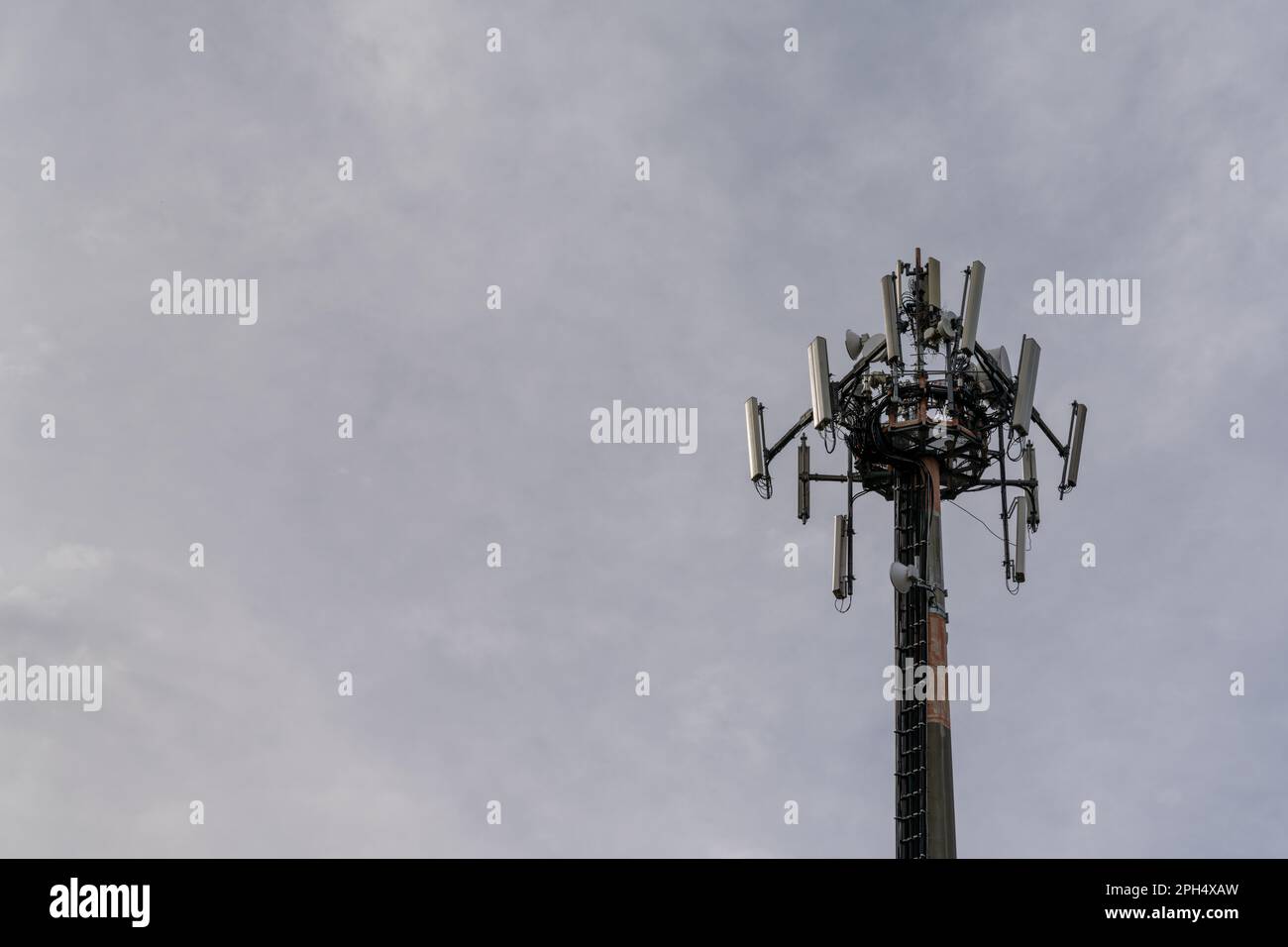 A close-up view of a cellphone and internet 5G antenna with overcast sky copy space Stock Photo