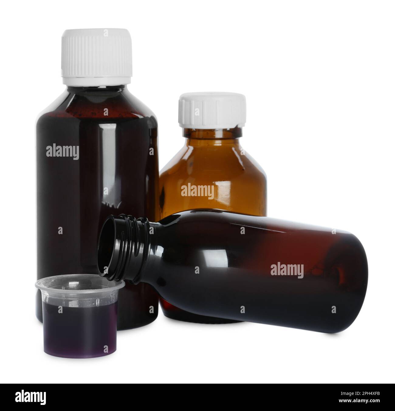 Bottles of cough syrup and measuring cup on white background Stock