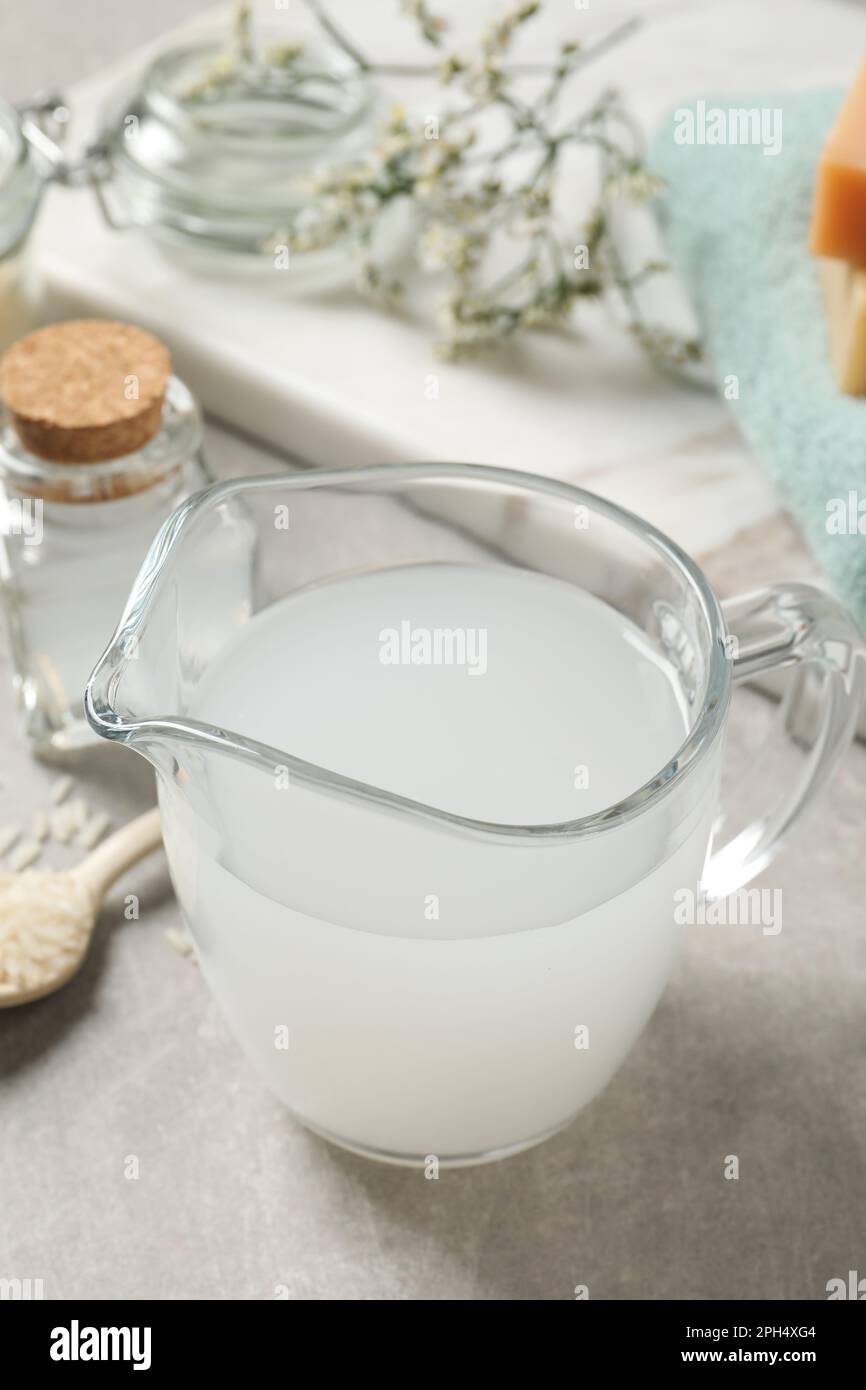Glass jug with natural rice water on light grey table, closeup Stock ...