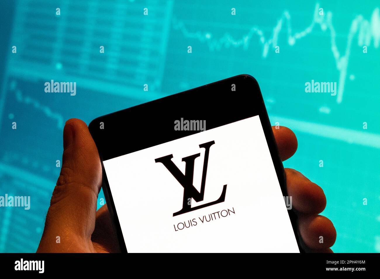 China. 15th Feb, 2023. In this photo illustration, the French luxury fashion brand Louis Vuitton (LV) logo seen displayed on a smartphone with an economic stock exchange index graph in the background. (Credit Image: © Budrul Chukrut/SOPA Images via ZUMA Press Wire) EDITORIAL USAGE ONLY! Not for Commercial USAGE! Stock Photo