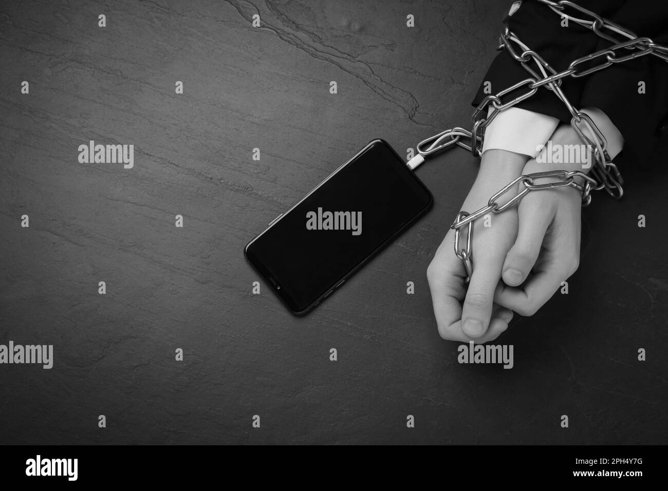 Top view of addicted woman chained to smartphone at dark table
