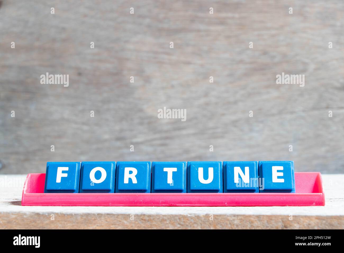 Tile alphabet letter with word fortune in red color rack on wood background Stock Photo
