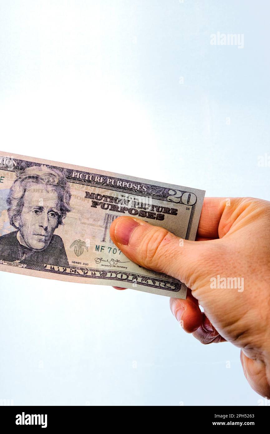 Man's hand holding a 20 dollar note, on a white background. Stock Photo