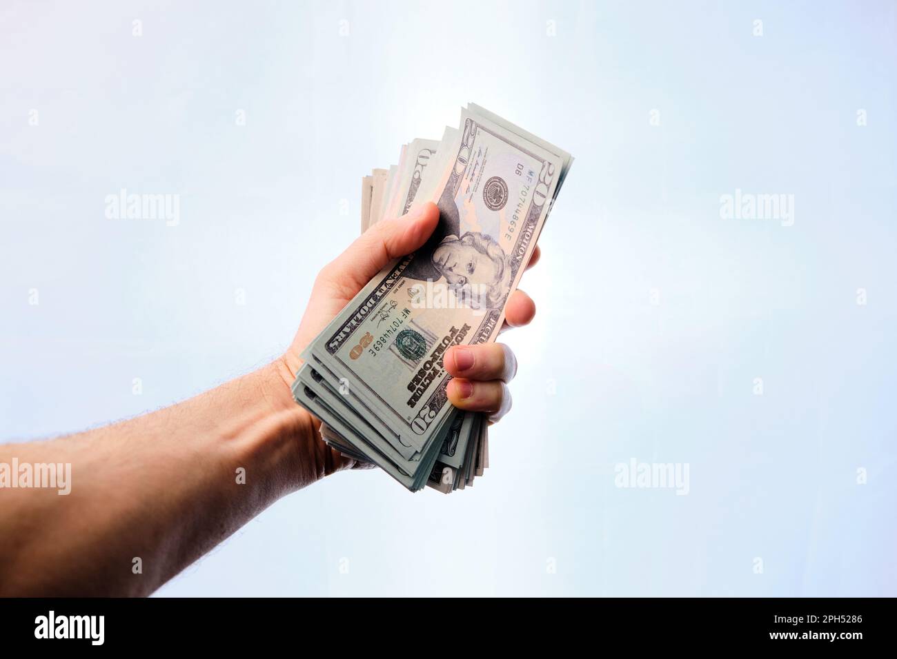 Man's hand clutching a pile of dollars, on a white background. Stock Photo