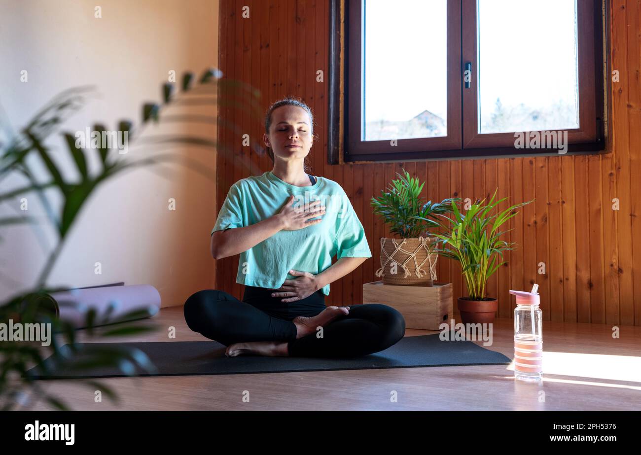 Woman doing breathing exercise sitting in lotus position Stock Photo