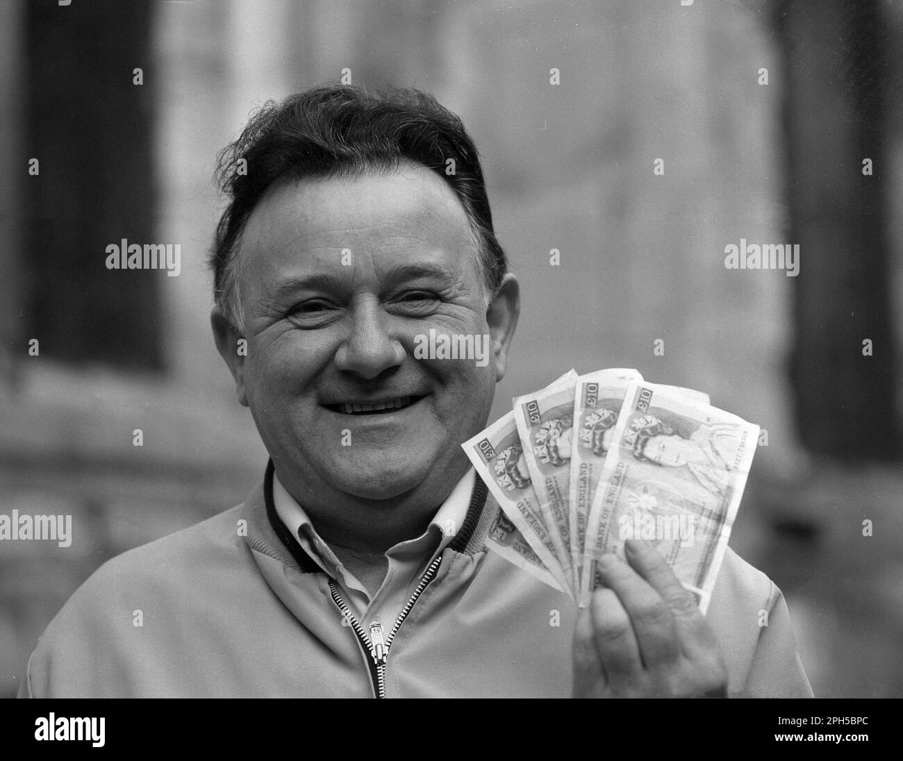 1986, historical, a happy gentleman holding up the cash - £50 in ten pound notes or tenners - he has won in a local newspaper competition, England, UK. Stock Photo