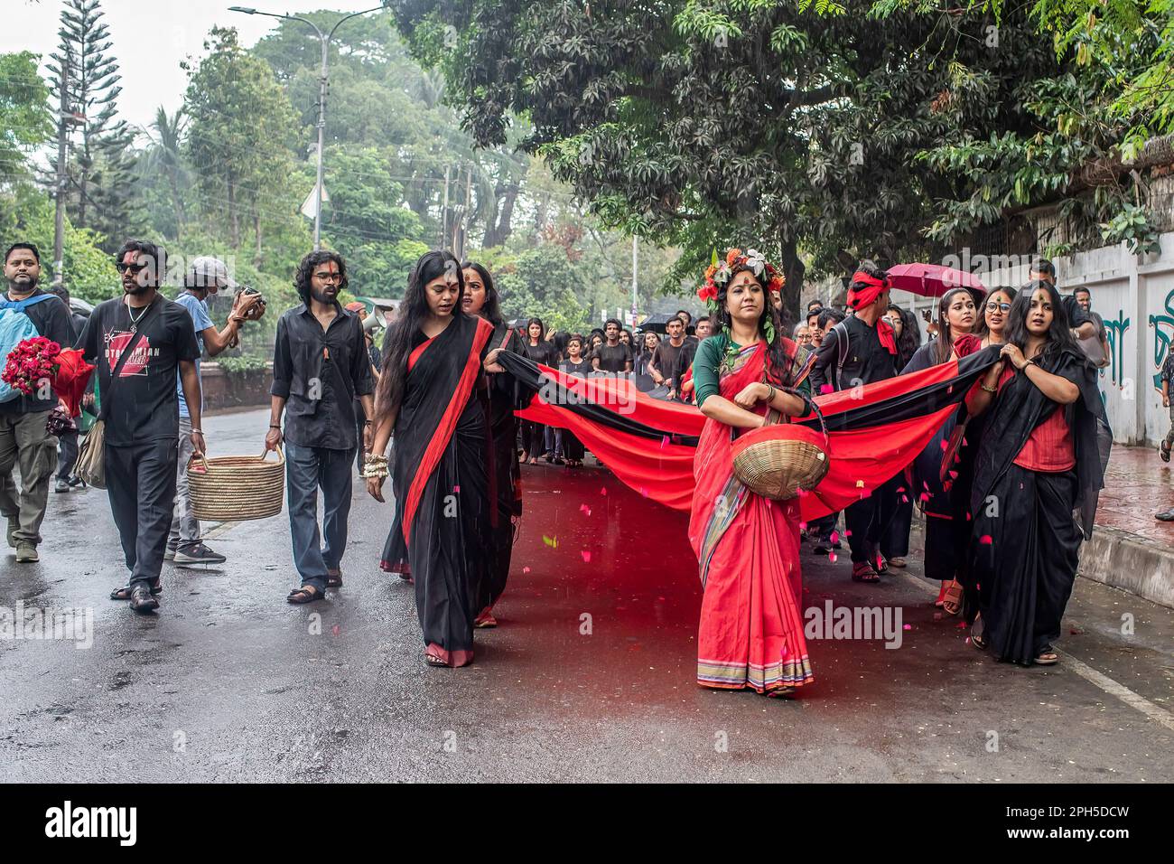 Prachyanat School of Acting and Design artists march with a banner during a performance of Lal Jatra (Red Procession) at the Dhaka University campus. Prachyanat School of Acting and Design held a procession of Lal Jatra (Red Procession), to remember the genocide by Pakistani Army on March 25, 1971 in Dhaka, Bangladesh on March 25, 2023. On this black night in the national history, the Pakistani military rulers launched ''Operation Searchlight'' killing some thousand people in that night crackdown alone. As part of the operation, tanks rolled out of Dhaka cantonment and a sleeping city woke up Stock Photo