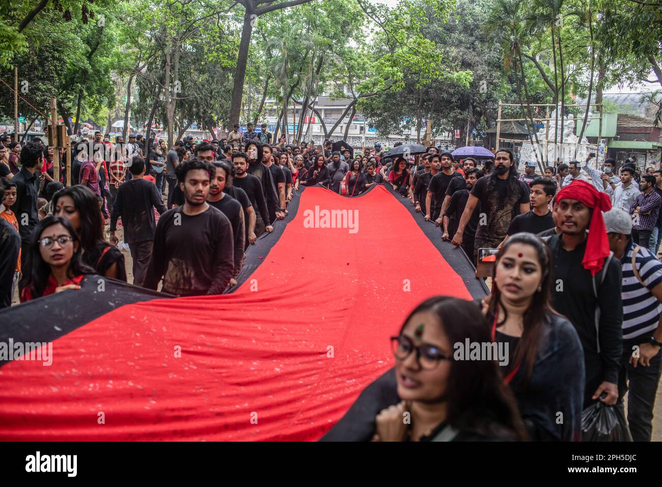 Prachyanat School of Acting and Design artists march with a banner during a performance of Lal Jatra (Red Procession) at the Dhaka University campus. Prachyanat School of Acting and Design held a procession of Lal Jatra (Red Procession), to remember the genocide by Pakistani Army on March 25, 1971 in Dhaka, Bangladesh on March 25, 2023. On this black night in the national history, the Pakistani military rulers launched ''Operation Searchlight'' killing some thousand people in that night crackdown alone. As part of the operation, tanks rolled out of Dhaka cantonment and a sleeping city woke up Stock Photo