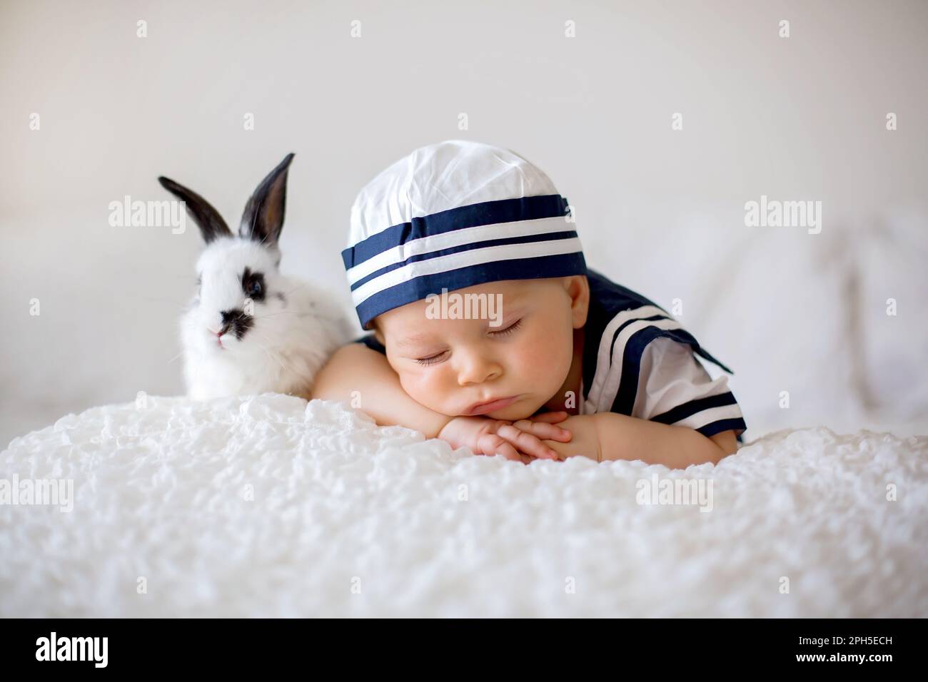 Cute baby boy, dressed in marine clothes, sleeping with wooden boat and