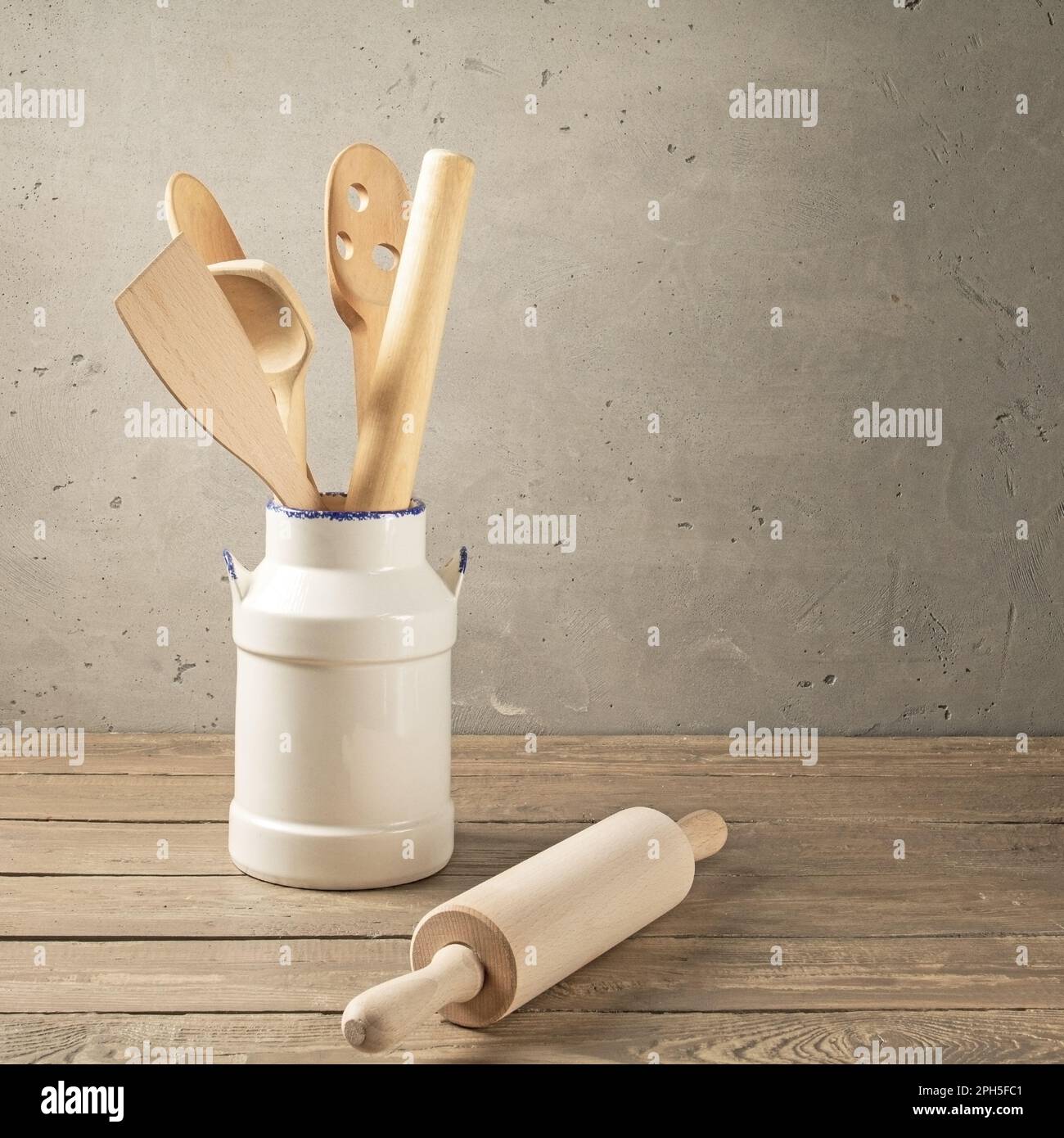 Wooden kitchen utensils. Various wooden tools in a clay vase on a table made of rough boards