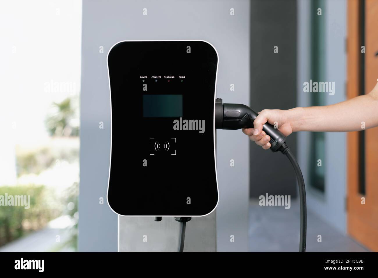 Closeup hand insert EV charger plug, green energypowered charging