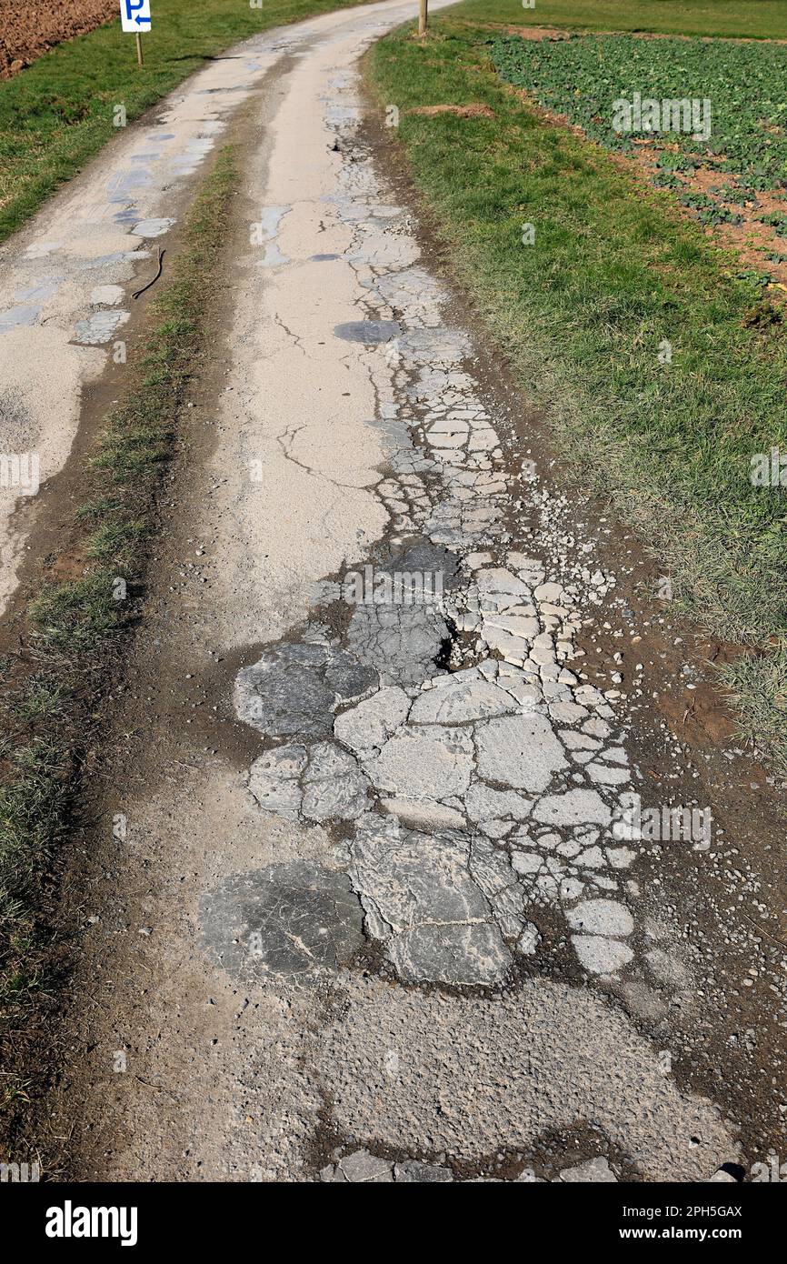 Dirt road is damaged and has cracks in the asphalt Stock Photo