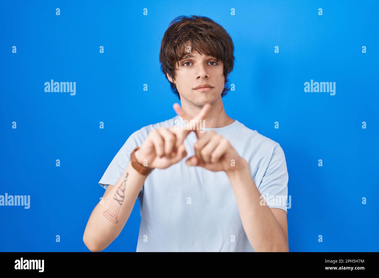 Hispanic young man standing over blue background rejection expression ...