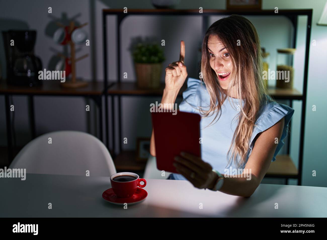Young hispanic woman using touchpad sitting on the table at night ...
