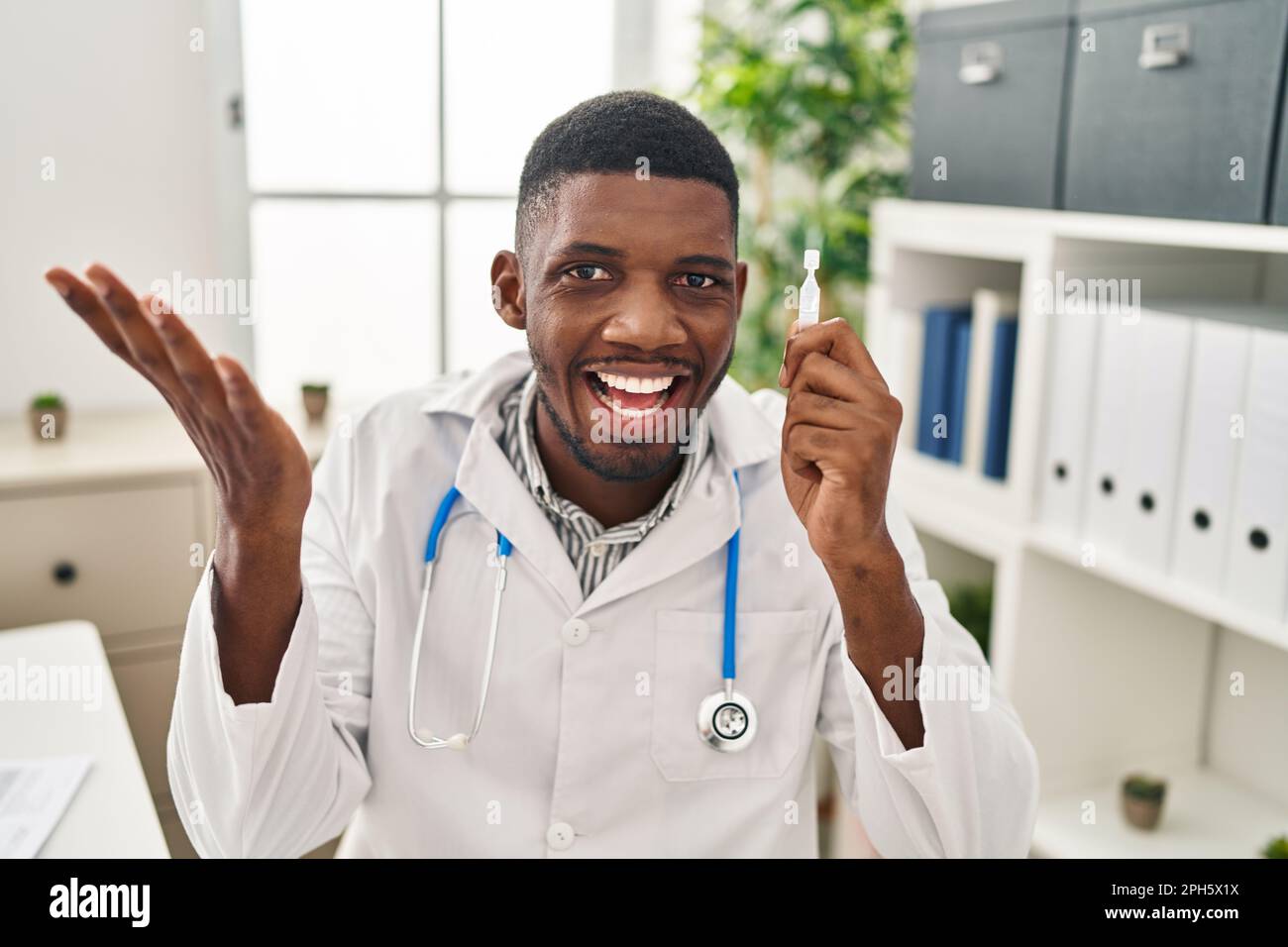 African American Doctor Man Holding Eye Drops Celebrating Achievement African American Doctor Man Holding Eye Drops Celebrating Achievement