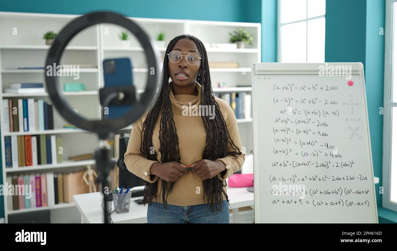 African woman recording teaching maths on magnetic board at library ...