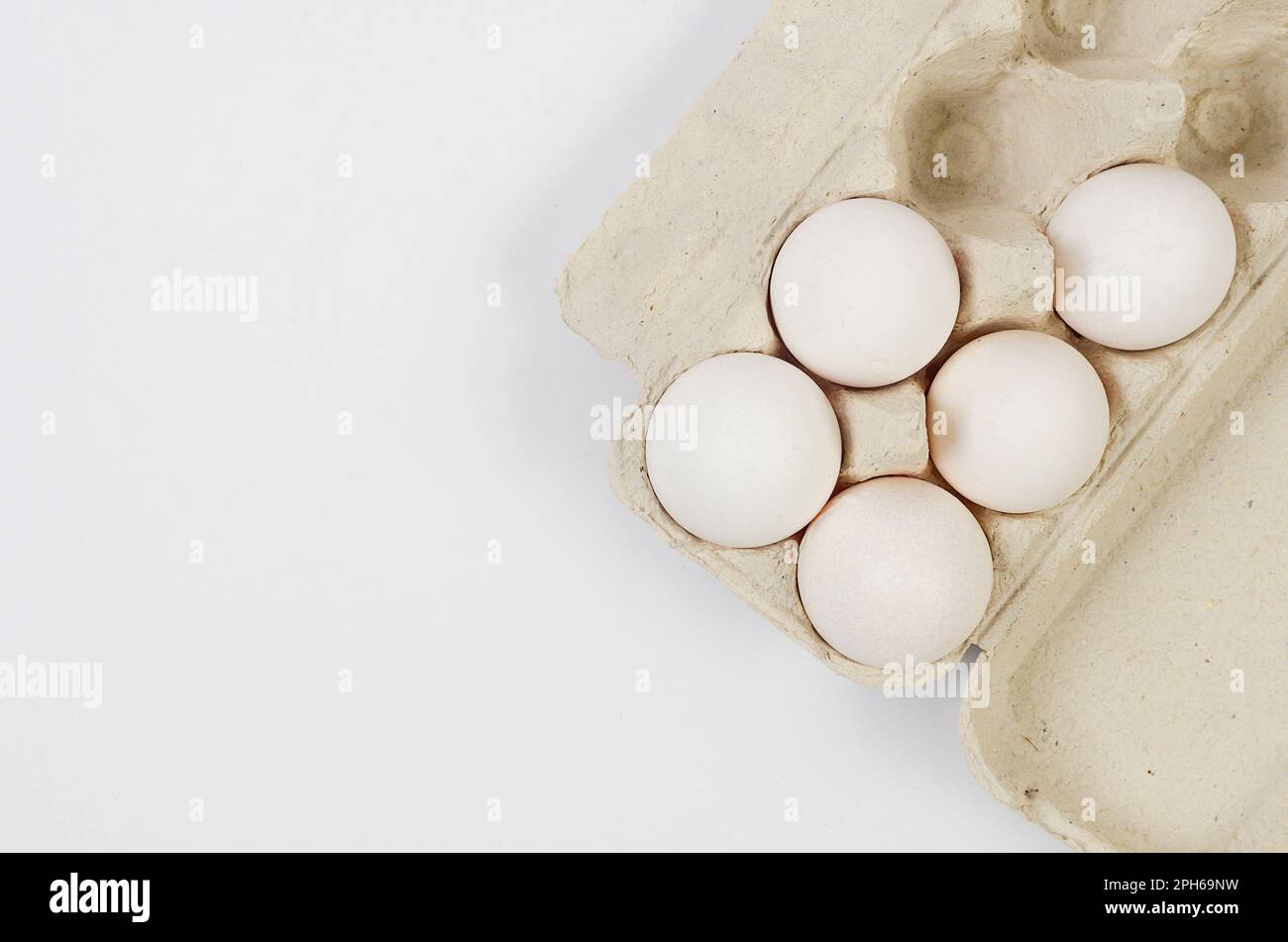 Fresh white chicken eggs in a cardboard tray close-up on white ...