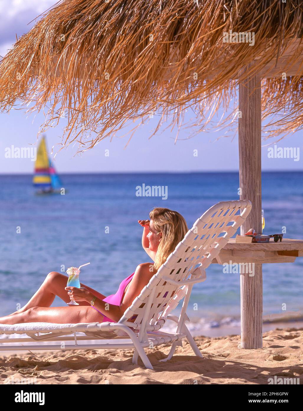 Young woman drinking cocktail on beach, Tamarind Cove, Barbados, Lesser Antilles, Caribbean Stock Photo