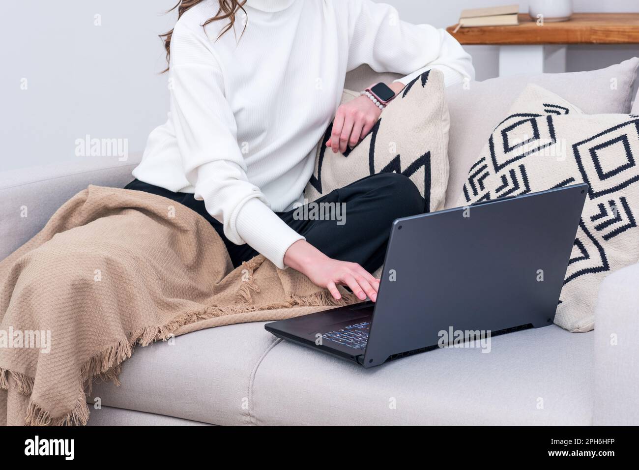 woman sitting on sofa indoor working with laptop Stock Photo