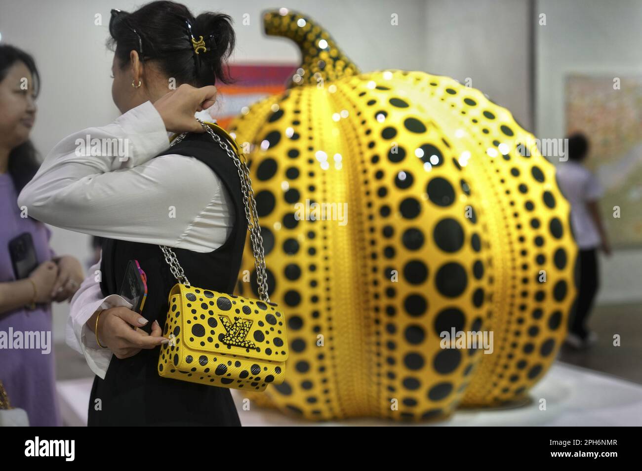 Art Basel Hong Kong 2023, the second day opening for invited people and  parties. Picture shows 'Pumpkin', a work by Japanese artist Yayoi Kusama,  and a visitor with a shoulder bag from