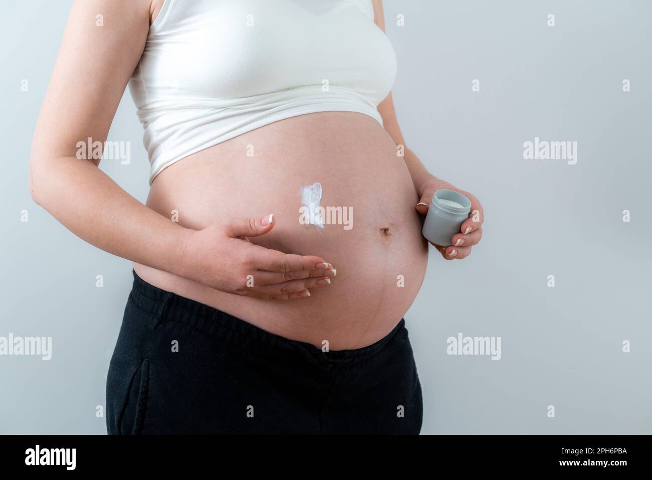 Pregnant woman applying white cream on the belly taking care of skin Stock Photo
