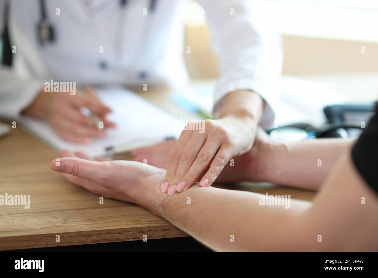 Doctor checkups patient pulse on wrist in medical office Stock Photo