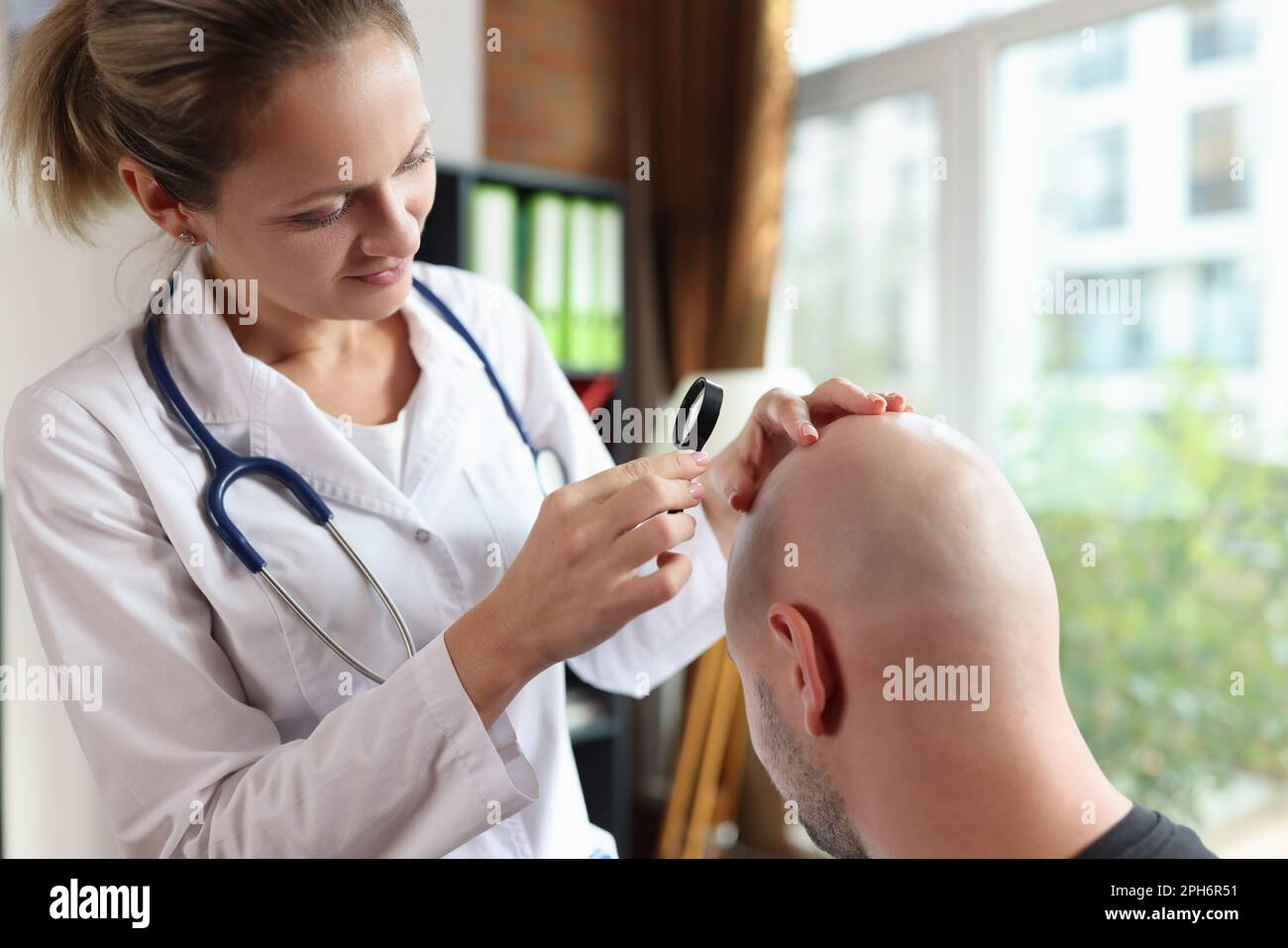 Doctor with magnifying glass checks patient head skin Stock Photo
