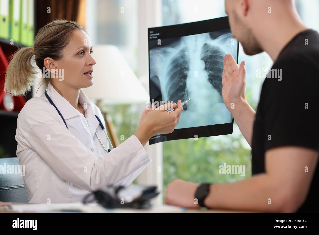 Family doctor shows x-ray picture to patient at appointment Stock Photo